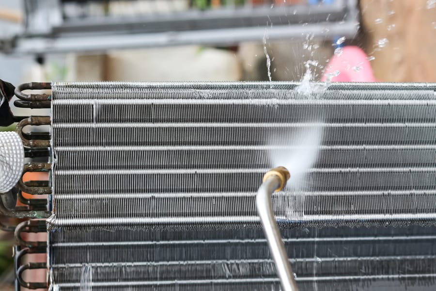 HVAC technician washing AC coils