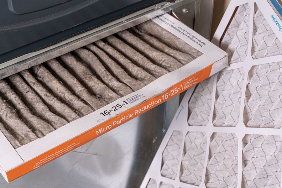 Car cabin air filter being replaced, showing pleated filter with an orange label reading Micro Particle Reduction 16x25x1
