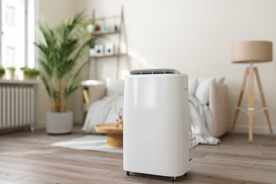 White portable air conditioner on wheels in a bright modern living room.