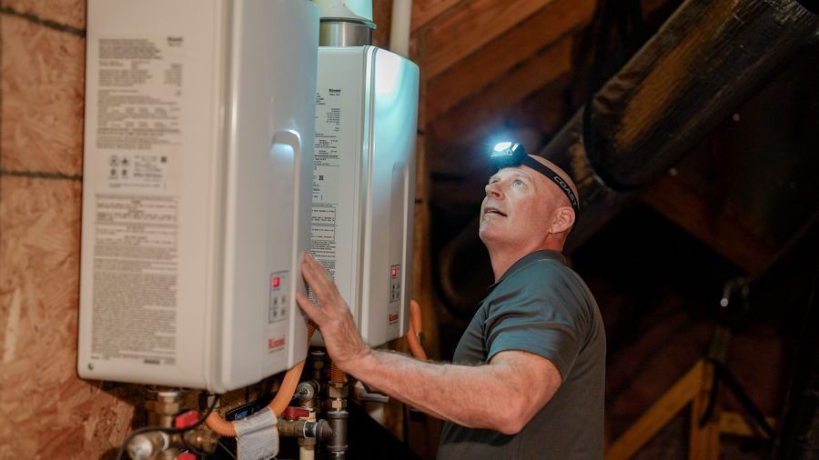 technician installing a tankless water heater in an attic