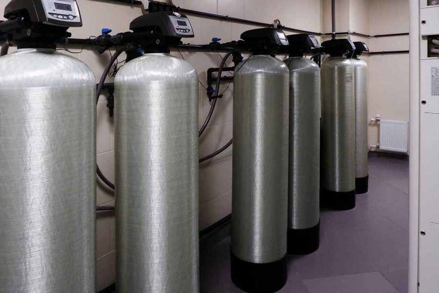 Multiple water softeners with silver tanks in a row