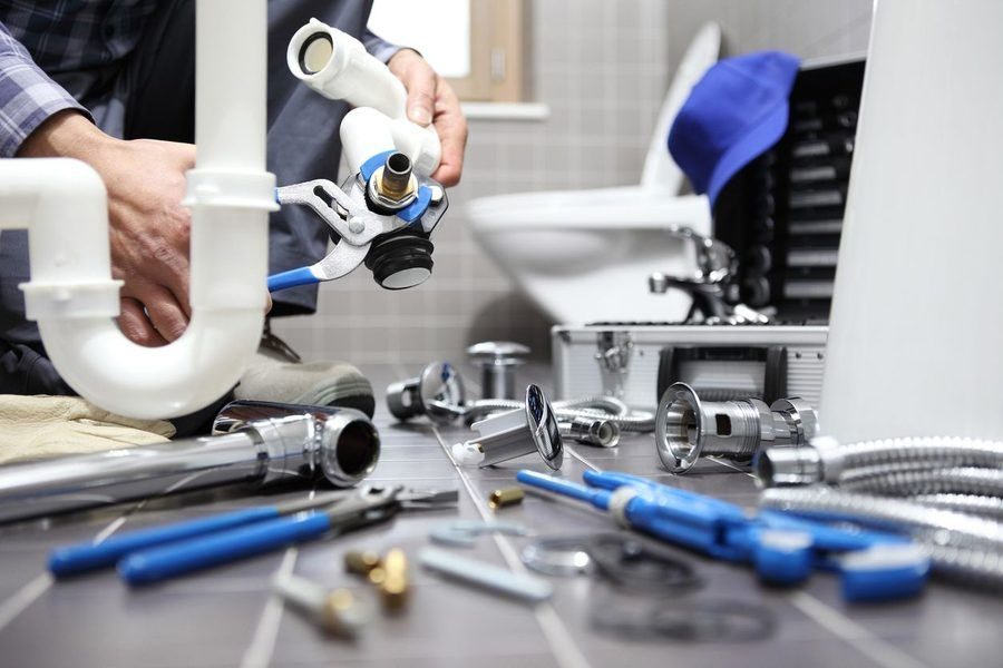 plumber working in a bathroom, fixing a toilet & drainage